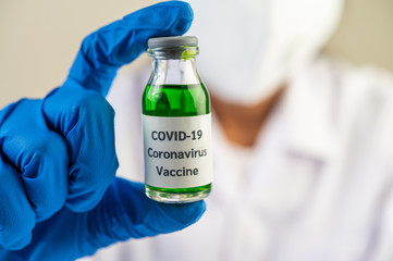 Scientists wearing masks and gloves, carrying vials with vaccines to protect Covid-19