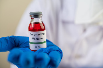 Scientists wearing masks and gloves, carrying vials with vaccines to protect Covid-19