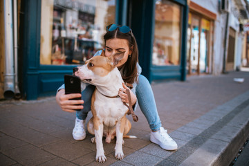  A beautiful young girl on the street taking photos of herself and her dog