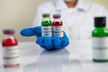 Scientists wearing masks and gloves, carrying vials with vaccines to protect Covid-19