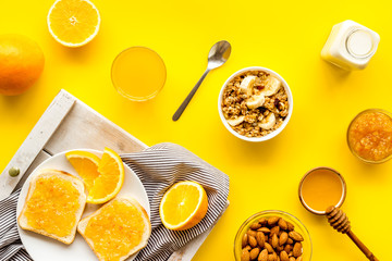 Granola for healthy breakfast. Still life composition with fruits and toast on yellow background top-down