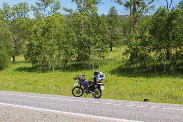 The motorcycle stands on the side of the road. Travel to the Altai Mountains. Stopping after a long trip