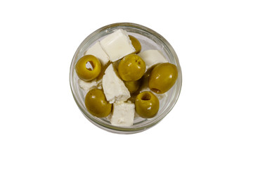 Feta cheese cubes with green olives in glass bowl isolated on white background. Top view