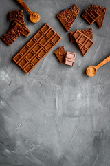 Homemade chocolate. Bars and broken pieces on grey stone table frame copy space