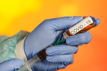 A blue-gloved medical worker draws an ampoule into a syringe. Medical vaccination against...