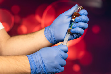A blue-gloved medical worker draws an ampoule into a syringe. Medical vaccination against coronavirus flu concept. injection bottle for medical glass vials. COVID pandemic
