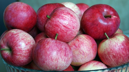 Fresh apples lie in a glass plate on a gray blurred background