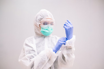 Young Nurse with disposable coverall wearing sterile gloves preparing take care of Pandemic 2019 Coronavirus 2019-nCoV.