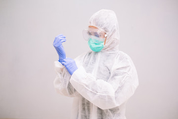 Young Nurse with disposable coverall wearing sterile gloves preparing take care of Pandemic 2019 Coronavirus 2019-nCoV.