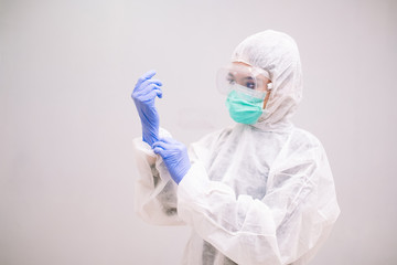 Young Nurse with disposable coverall wearing sterile gloves preparing take care of Pandemic 2019 Coronavirus 2019-nCoV.