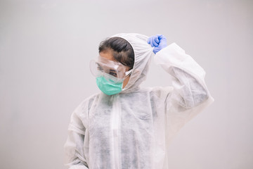 Tired Young Nurse take off disposable coverall with mask and safety googles after take care of Pandemic 2019 Coronavirus 2019-nCoV.