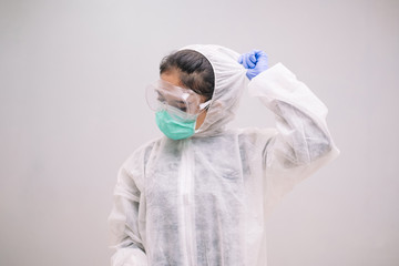 Tired Young Nurse take off disposable coverall with mask and safety googles after take care of Pandemic 2019 Coronavirus 2019-nCoV.