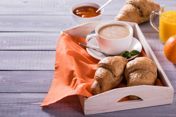 breakfast with fresh croissants and coffee on wooden table