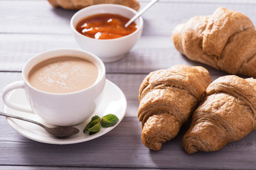 breakfast with fresh croissants and coffee on wooden table