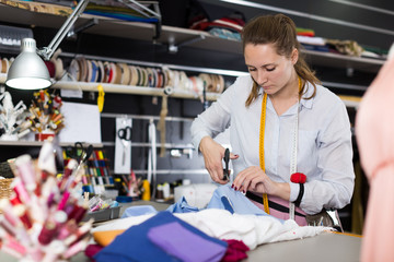 Female seamstress is cutting textile for create new dress