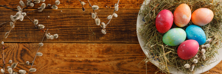 Still life of easter eggs in a bird's nest on a wooden background. Rustic. Easter celebration concept. Copy space. Flat lay. Banner.