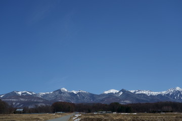 青空を背景に雪が残る山里の早春