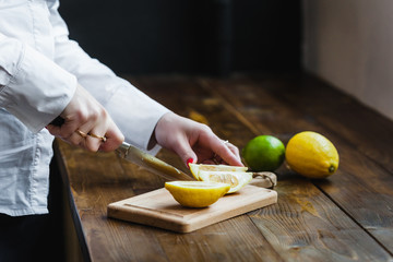 Board with lemon and lime for slicing, preparing for cooking, salads and appetizers, lemon juice, decorating dishes, cook, man cutting a lemon, holding a kitchen knife in his hand, cutting a lime