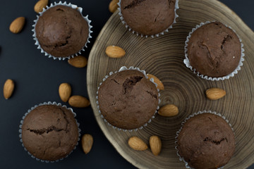 Top view simple chia seed chocolate muffins with almonds on a black background with wood slice accent