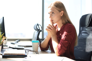 Frustrated business woman looking exhausted while sitting at her working place