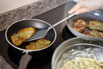 Process frying zucchini pancakes in frying pan in kitchen