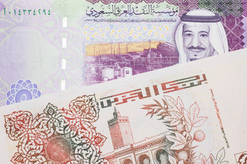 A beige, two hundred Algerian dinar bill with a colorful five Saudi riyal bank note close up in macro