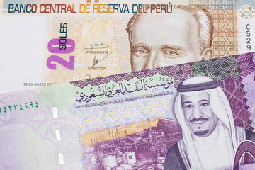A pastel colored, twenty Peruvian sol bank note, close up in macro with a colorful Saudi five riyal bank note