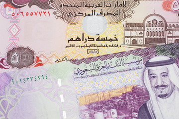 A colorful, five Saudi riyal bank note with a five dirham bank note from the United Arab Emirates close up in macro