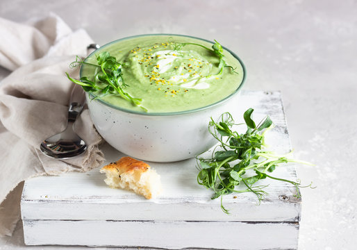 Vegan cream soup with avocado and spinach served with micro greens and bread. Diet food concept. Vegetarian and vegan food. 