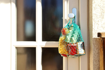 delivery during the quarantine. Shopping bag with Merchandise, goods and food is hanging at the...