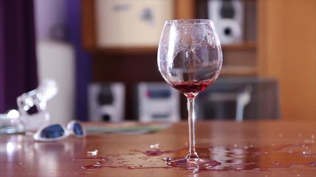 Gunshot a glass of wine, two gunshots on the glass with red wine.