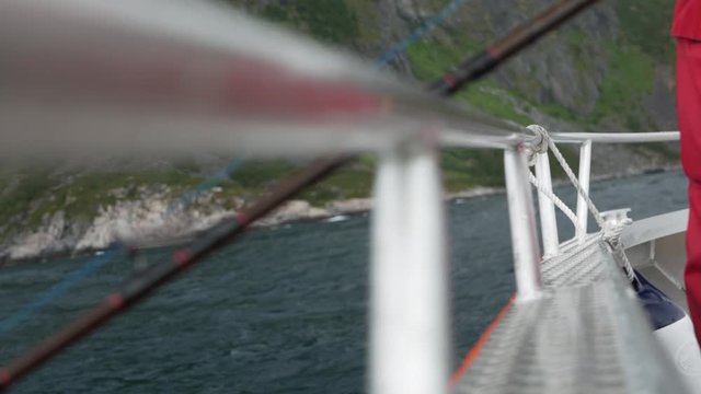 Fishing rod over side of aluminium boat rocking in the water with rugged landscape