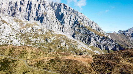 A drone shot of a pathway in Alps. The road is curvy, but steadily leading to the top. Golden...