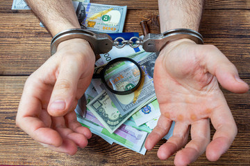 handcuffed hands on a money banknotes background.