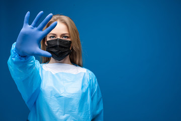 Stock photo portrait of a Caucasian adult woman in black respiratory mask, blue robe and rubber...