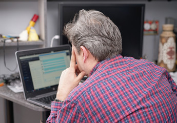 gray-haired man works in the room at the home-office