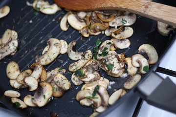 Fried champignon mushroom with parsley in skillet