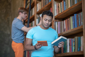 Two friends looking for the needed books in the library