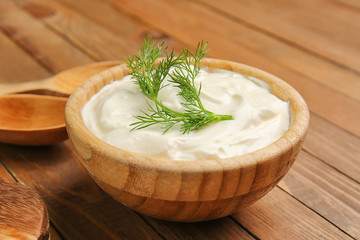 Bowl with tasty sour cream on table