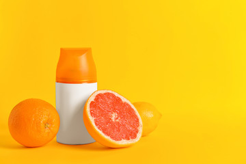 Bottle of air freshener and citrus fruits on color background