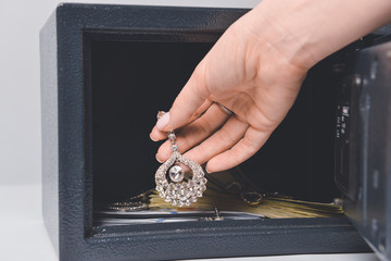 Woman taking valuables from safe box, closeup