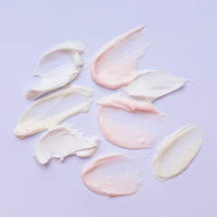 Samples of cosmetic cream on color background