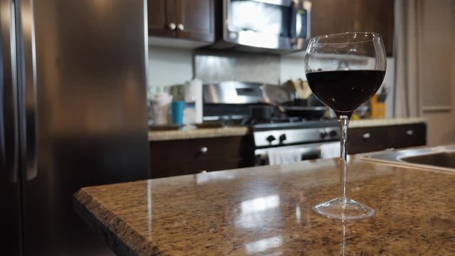 Single glass of wine in kitchen, focus on wine with blurred background