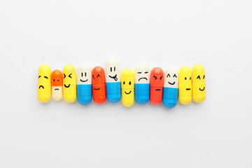 Pills with drawn faces on white background