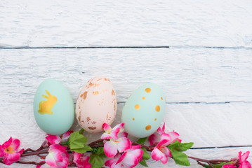 colorful easter eggs and branch with flowers on white wood
