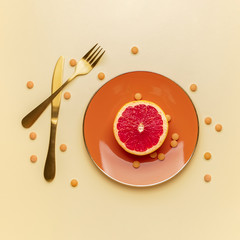 Plate with weight loss pills and grapefruit on color background