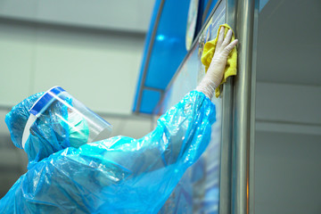 solders wearing rain cover, mask, glove, and plastic shield cleaning airport area to protect corona...
