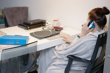 woman in a bathrobe works remotely at home-office