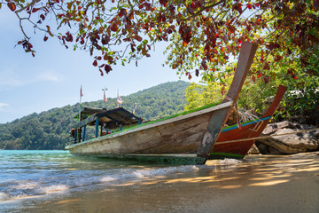 A classic wooden local passenger longtail boat is on the sand beach, waiting for next departure time. Here is Surin national island, most famous paradise island in Andaman ocean - Thailand.