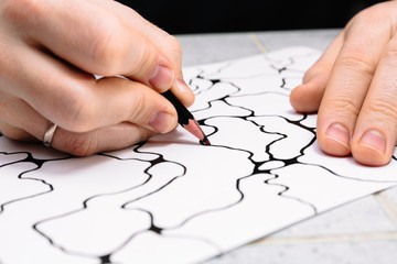 Man is drawing an abstract imaginary picture of curves by a black pencil in his hand. A...